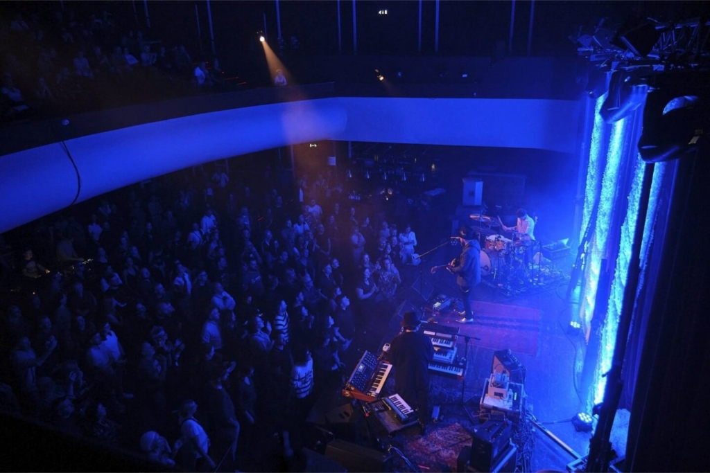 Zespół muzyczny na scenie na widowni stoją ludzie