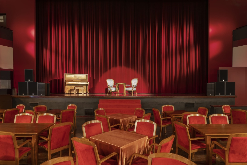 Scena, na której stoją krzesła, stolik i pianino