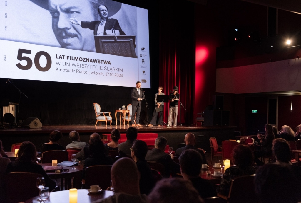 Na środku sceny goście, na widowni przy stolikach siedzą ludzie